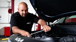 Kia tech working under hood of vehicle